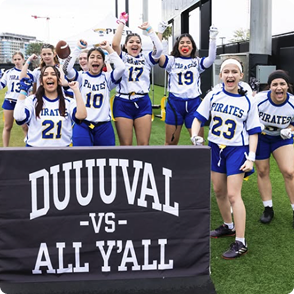 Flag football team posing behind a Duuuval versus All Yall banner.